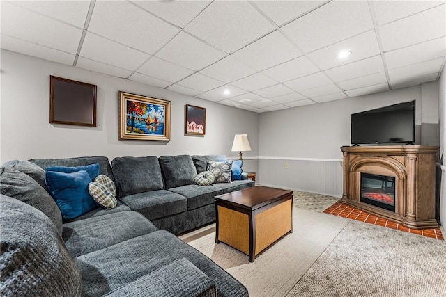 living room featuring recessed lighting, a glass covered fireplace, wainscoting, and a drop ceiling