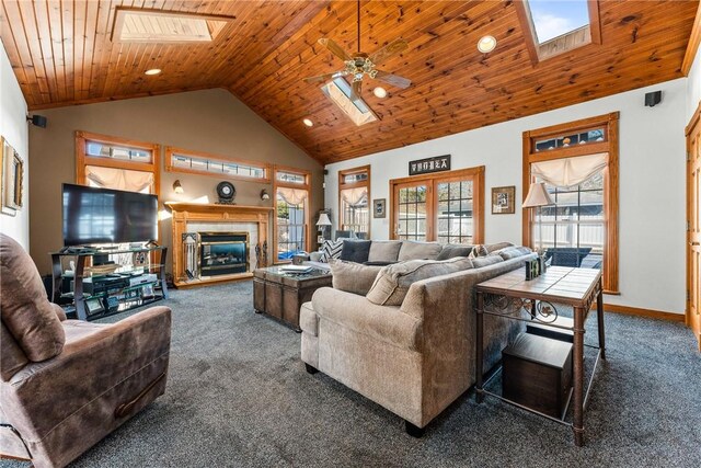 carpeted living area featuring baseboards, high vaulted ceiling, a skylight, ceiling fan, and wood ceiling