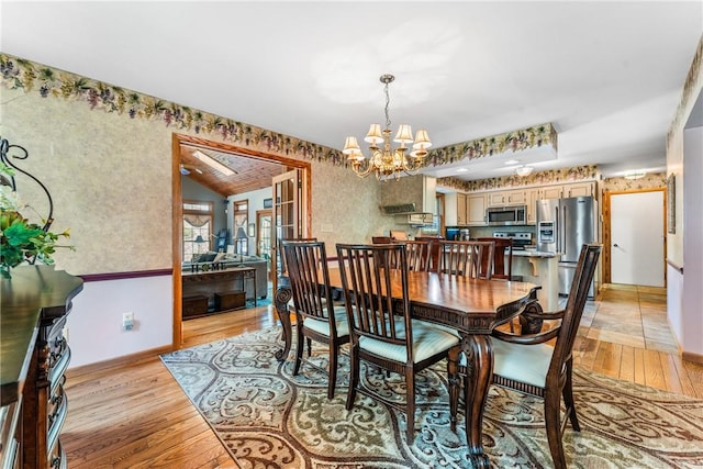 dining room with a chandelier, wallpapered walls, and light wood-type flooring