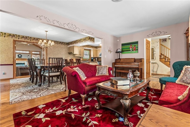 living area with a chandelier, baseboards, wood finished floors, and stairs