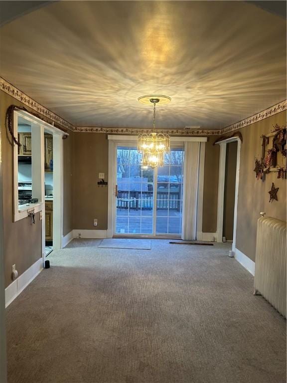 carpeted empty room featuring a notable chandelier, radiator, and baseboards