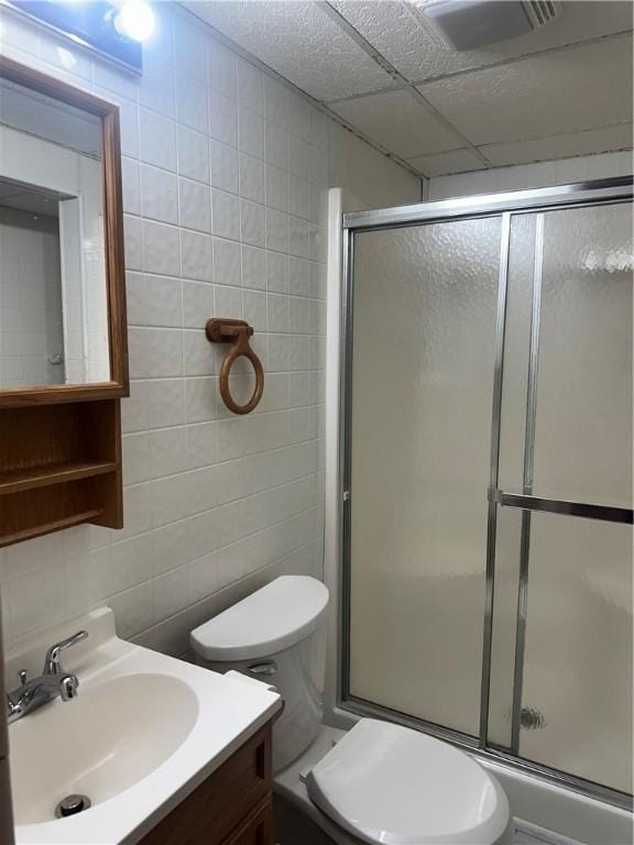 bathroom featuring vanity, toilet, tile walls, and a shower stall