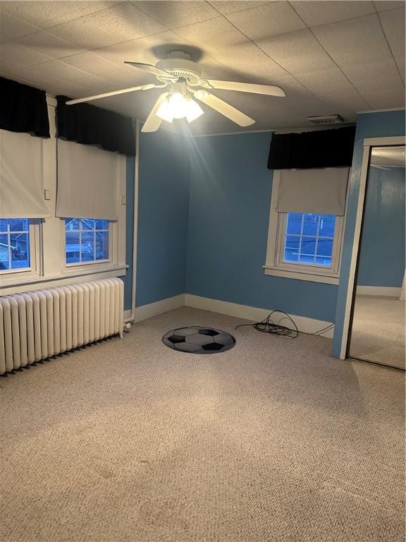 spare room featuring visible vents, radiator, baseboards, carpet floors, and a ceiling fan