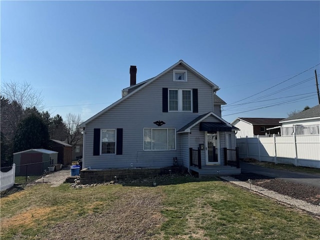 view of front of property with a chimney, a front lawn, and fence