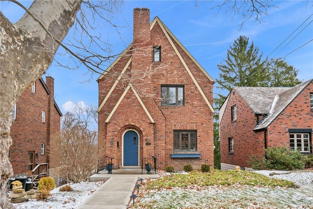 tudor-style house featuring brick siding and a chimney