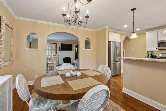 dining space with baseboards, dark wood-style flooring, and arched walkways