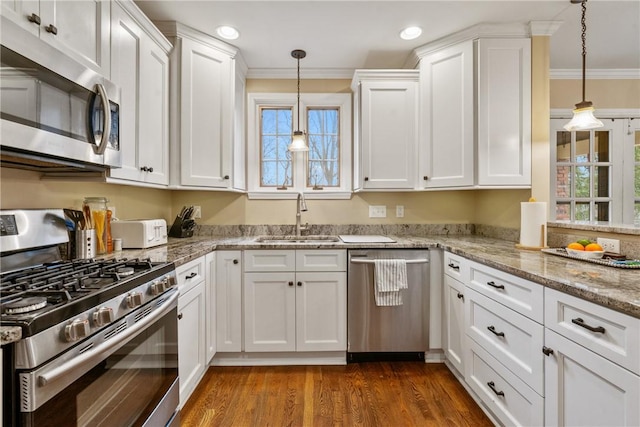 kitchen with ornamental molding, appliances with stainless steel finishes, white cabinets, and a sink