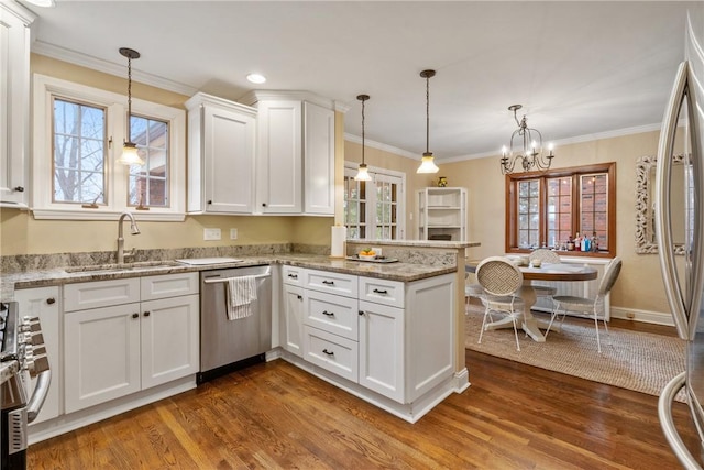 kitchen with ornamental molding, a peninsula, white cabinets, stainless steel appliances, and a sink