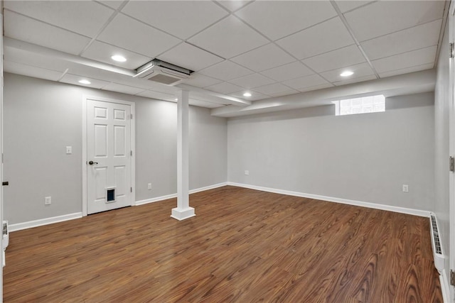 finished below grade area with recessed lighting, a drop ceiling, baseboards, and wood finished floors