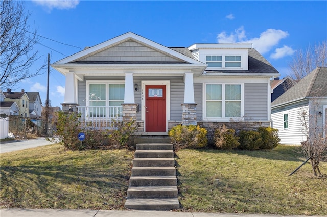 craftsman-style home with stone siding, covered porch, and a front yard