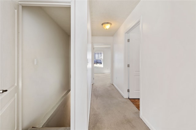 hall featuring baseboards, carpet floors, and a textured ceiling