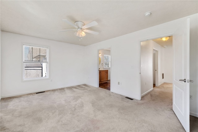 unfurnished bedroom featuring visible vents, ensuite bathroom, and carpet