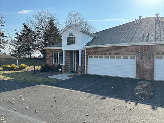 traditional-style home featuring brick siding, an attached garage, driveway, and roof with shingles