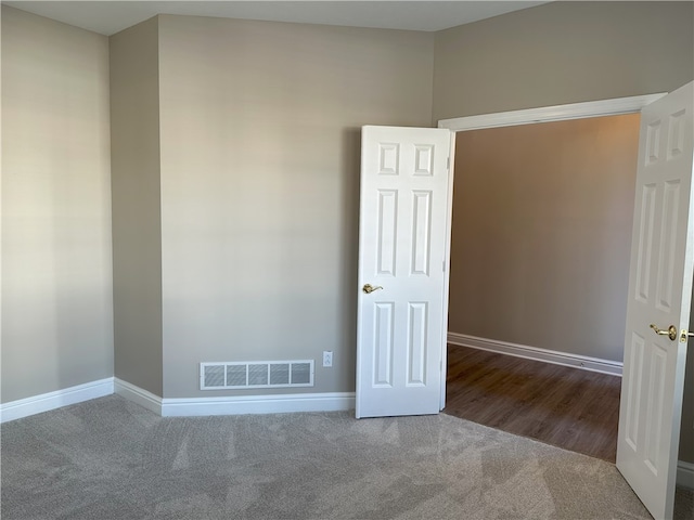 carpeted spare room with visible vents and baseboards