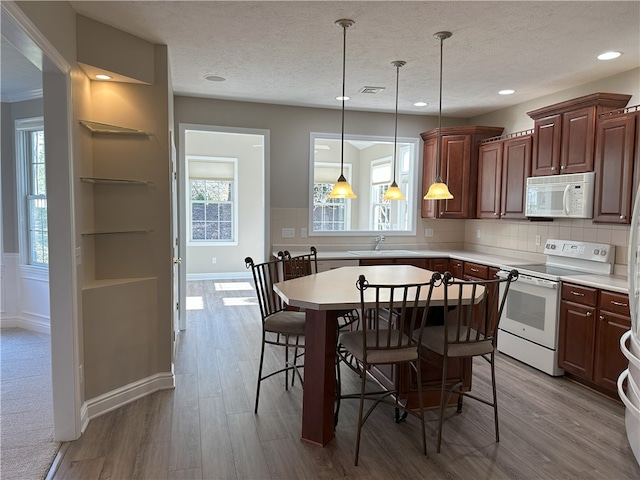 kitchen featuring white appliances, a breakfast bar area, a sink, light countertops, and tasteful backsplash