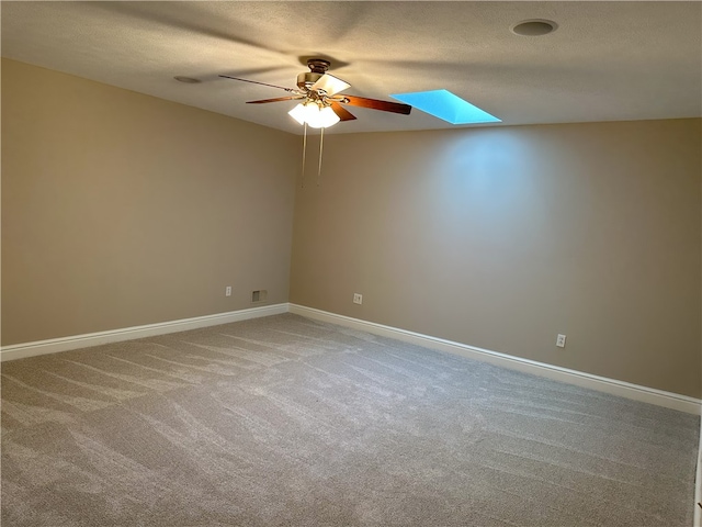 unfurnished room featuring ceiling fan, a skylight, carpet, and a textured ceiling