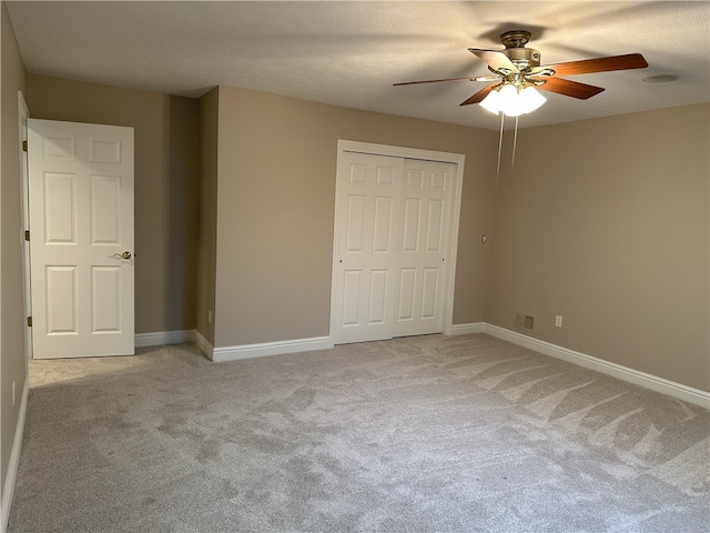 unfurnished bedroom with a closet, visible vents, light colored carpet, and baseboards