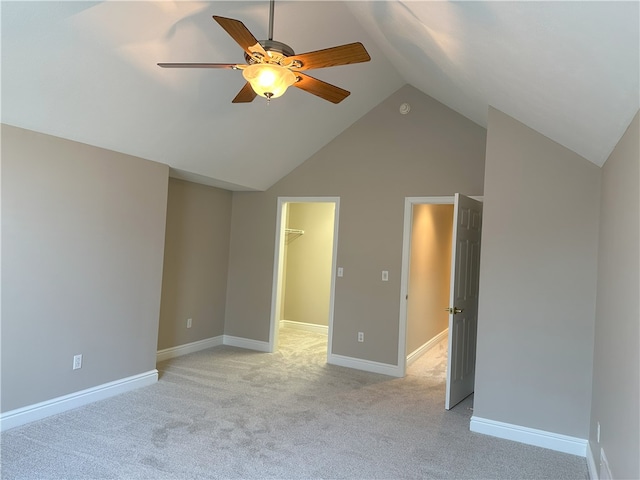 unfurnished bedroom with baseboards, light colored carpet, a spacious closet, and vaulted ceiling