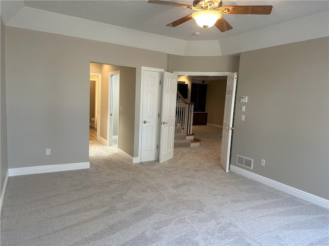 unfurnished bedroom featuring visible vents, baseboards, light colored carpet, and a ceiling fan