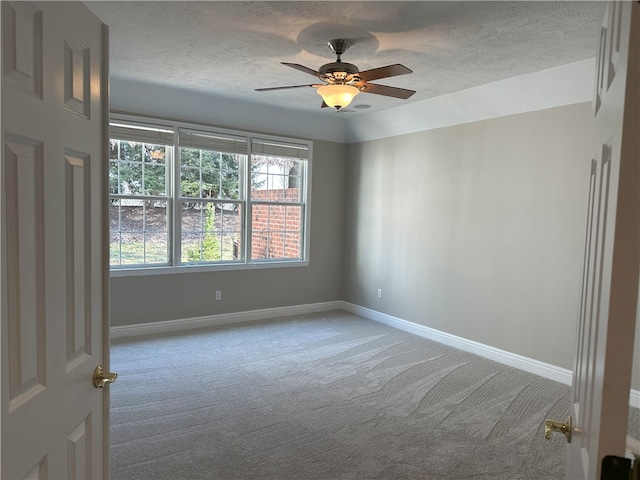 carpeted empty room featuring ceiling fan, baseboards, and a textured ceiling