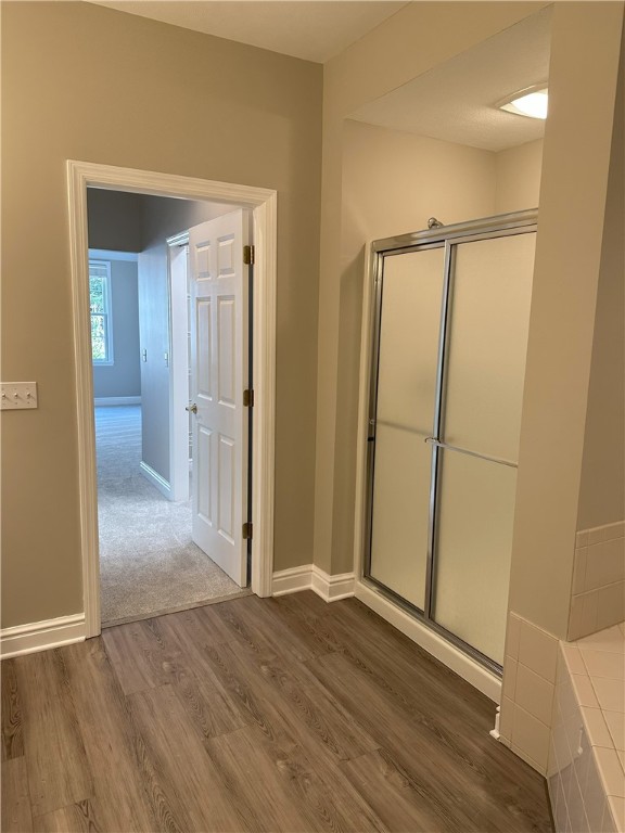 bathroom with an enclosed shower, wood finished floors, and baseboards