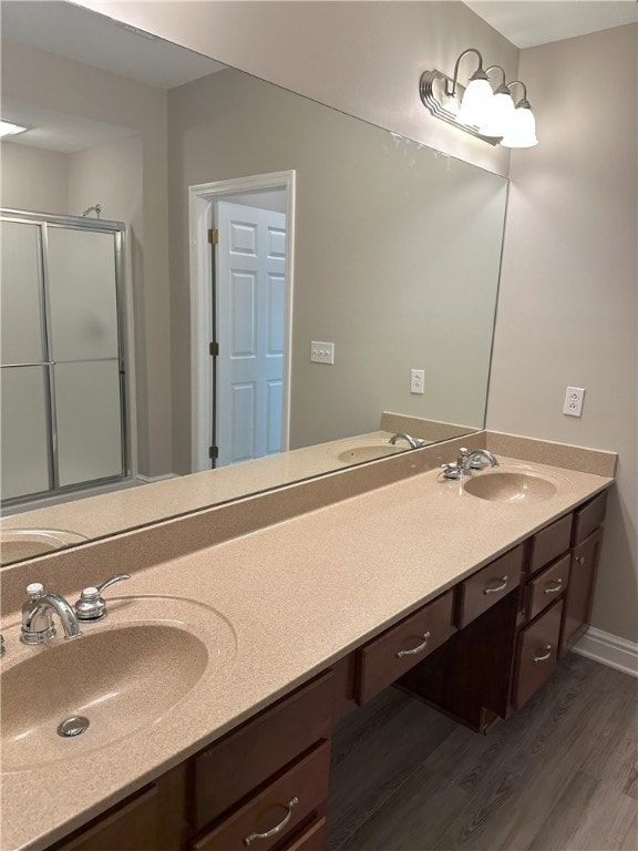 full bath featuring double vanity, a stall shower, wood finished floors, and a sink