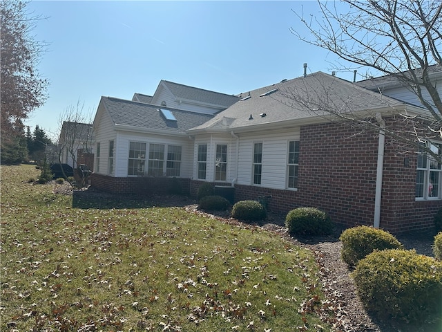 view of side of property featuring brick siding and a lawn