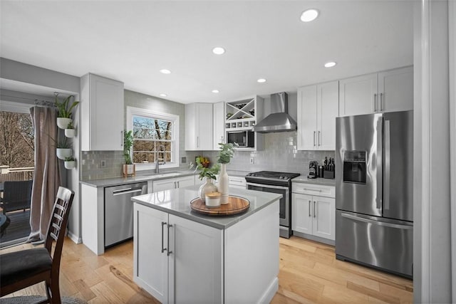 kitchen featuring a sink, wall chimney exhaust hood, light wood-style floors, and stainless steel appliances