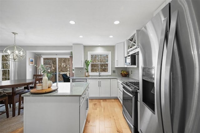 kitchen featuring a kitchen island, stainless steel appliances, light wood-style floors, white cabinets, and decorative backsplash