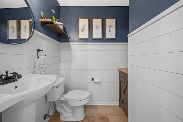 bathroom featuring toilet, wood finished floors, and wainscoting