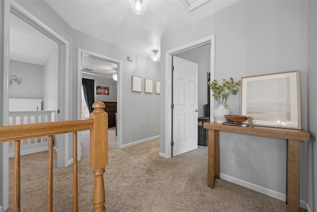 hall with an upstairs landing, baseboards, and carpet floors