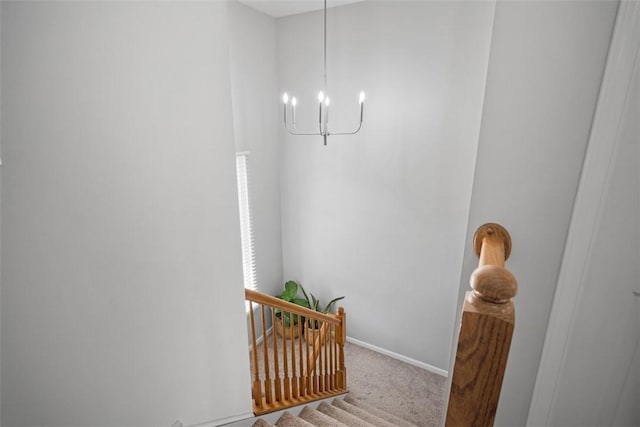 stairs with an inviting chandelier, carpet, and baseboards