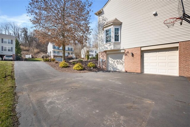 view of property exterior featuring aphalt driveway, an attached garage, and brick siding