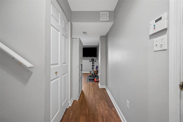 corridor with visible vents, baseboards, and dark wood-style floors