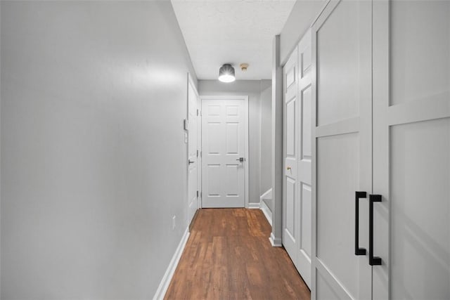 hall featuring dark wood-type flooring, baseboards, and a textured ceiling