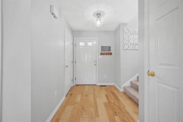 doorway with stairway, light wood-style flooring, and baseboards