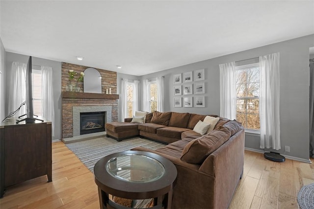 living room with a fireplace, baseboards, and light wood finished floors