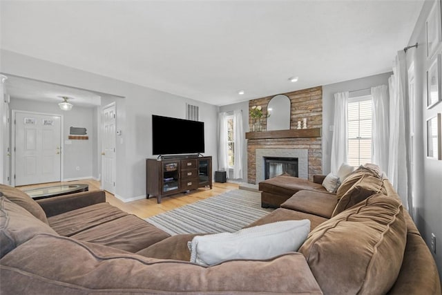 living room with visible vents, baseboards, wood finished floors, and a fireplace