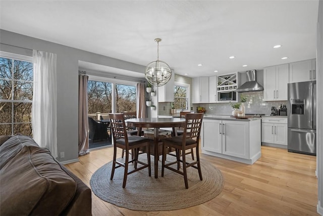 dining room with recessed lighting, light wood-style flooring, and an inviting chandelier