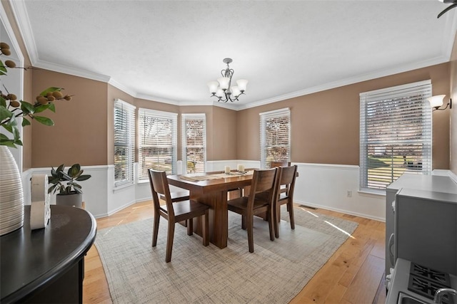 dining area with a chandelier, a healthy amount of sunlight, light wood-type flooring, and ornamental molding