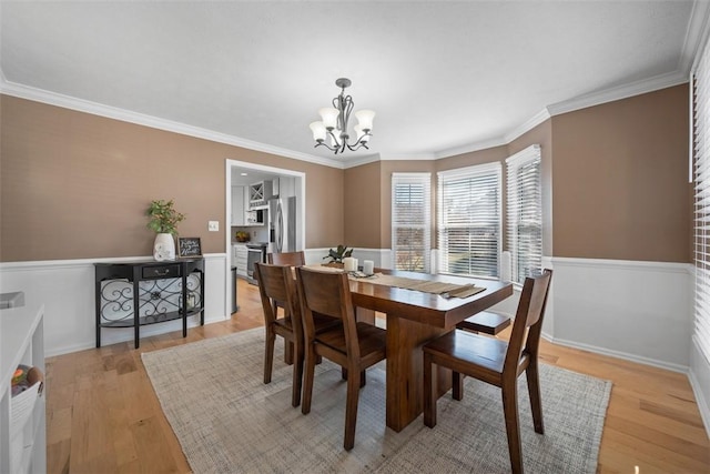 dining room featuring crown molding, light wood finished floors, and a chandelier