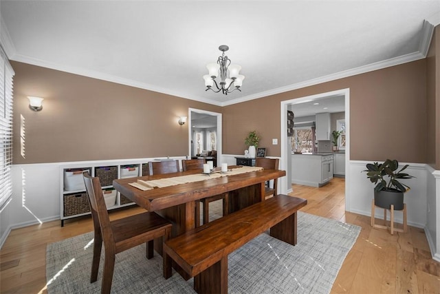 dining area featuring a notable chandelier, light wood-style flooring, and ornamental molding