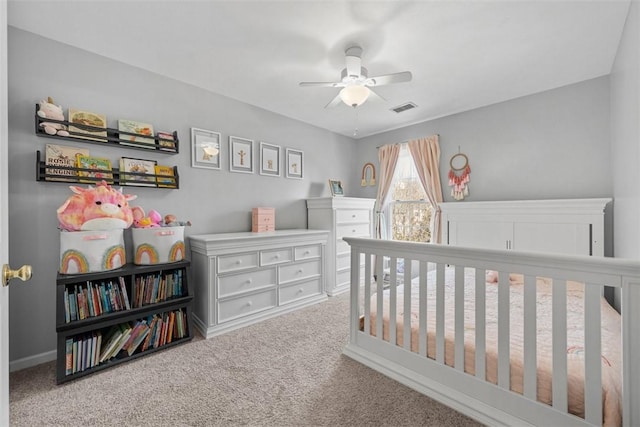 bedroom with visible vents, carpet floors, a crib, and a ceiling fan