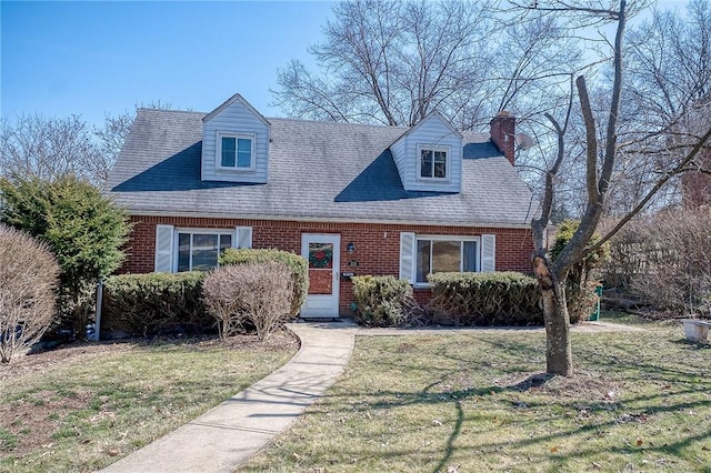 new england style home featuring brick siding and a front yard