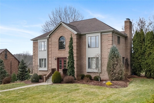 view of front facade featuring brick siding, a chimney, and a front yard