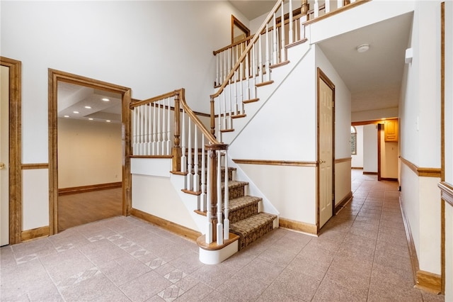 stairway featuring baseboards and a towering ceiling