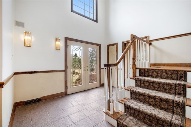 foyer entrance with visible vents, baseboards, a high ceiling, stairs, and french doors