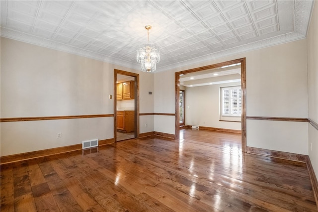 empty room featuring visible vents, an ornate ceiling, baseboards, and wood finished floors