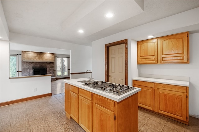 kitchen with baseboards, stainless steel gas cooktop, recessed lighting, light countertops, and a brick fireplace