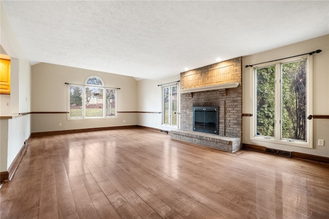 unfurnished living room with wood finished floors, a fireplace, and a wealth of natural light